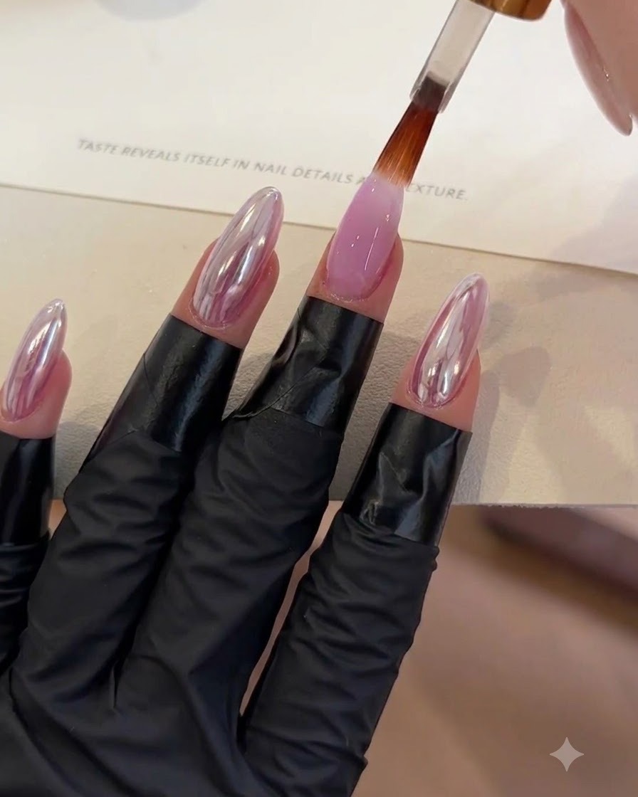 Un pincel aplicando una capa de brillo superior transparente sobre una uña de gel morado.