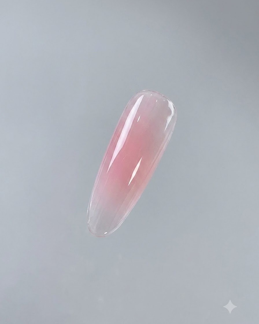 Una uña individual terminada que muestra una capa base rosa brillante y curada sobre un fondo neutral.