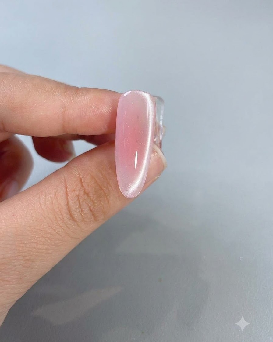 Un primer plano de una uña rosa cat-eye terminada que muestra una línea brillante de reflejo de luz corriendo por el lateral.