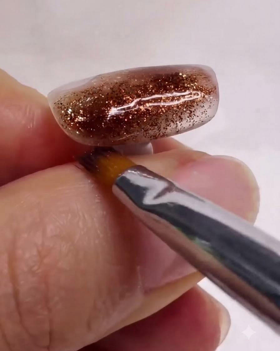 Un pincel de arte de uñas limpio alisando y mezclando suavemente capas de mármol blanco y marrón en una uña texturizada.