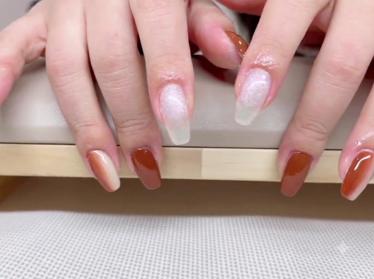 Una vista de manos que muestra esmalte en gel marrón caramelo intenso en el pulgar, anular y meñique.