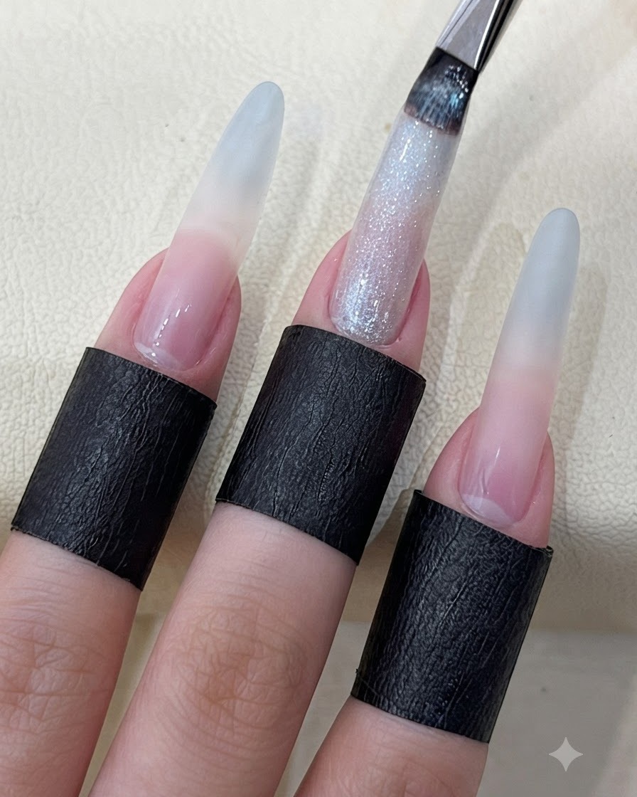 Un pincel de uñas aplicando gel brillante de ojo de gato estrellado sobre una uña larga esculpida.