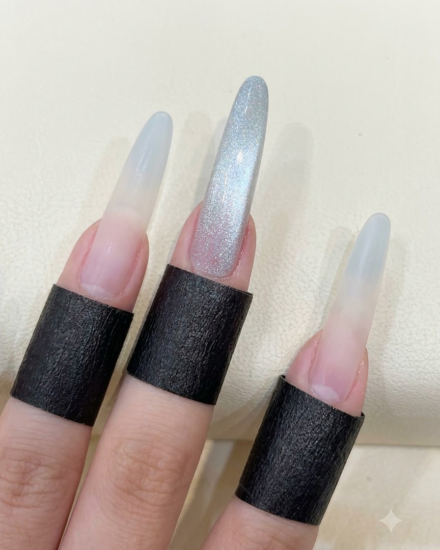 Una mano mostrando uñas largas en almendra con el reflejo completo de ojo de gato en cuenta de vidrio.