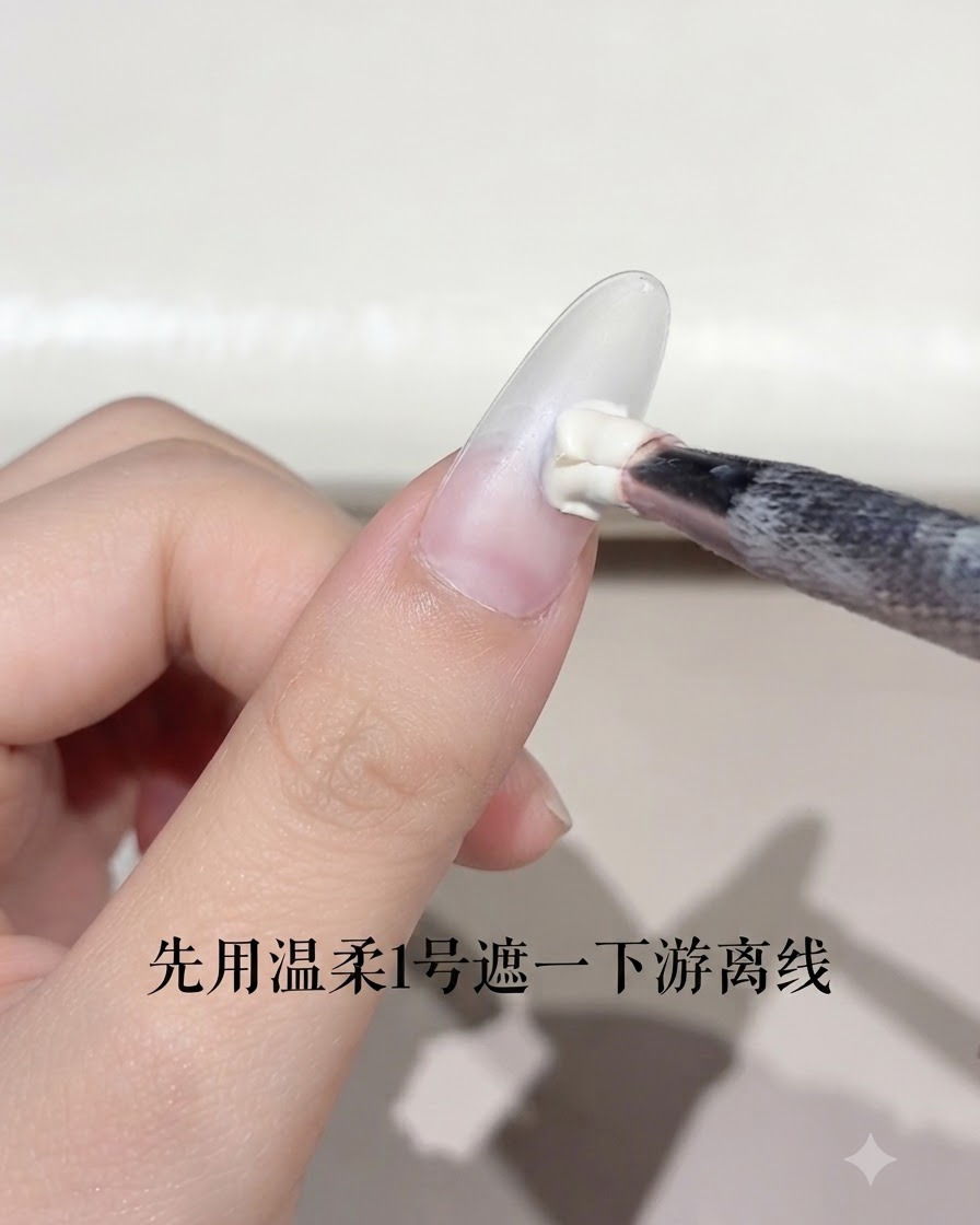 Un pincel de uñas aplicando una pequeña cantidad de gel blanco en el borde libre de una uña en forma de almendra.