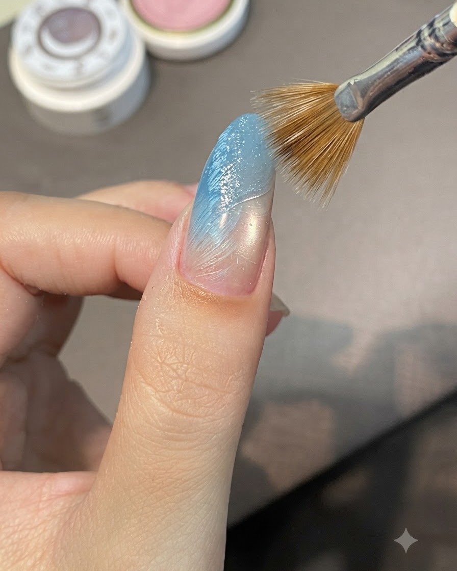 Un pincel de líneas barriendo diagonalmente a través de gel de esculpido húmedo en una uña con degradado azul para formar crestas elevadas.