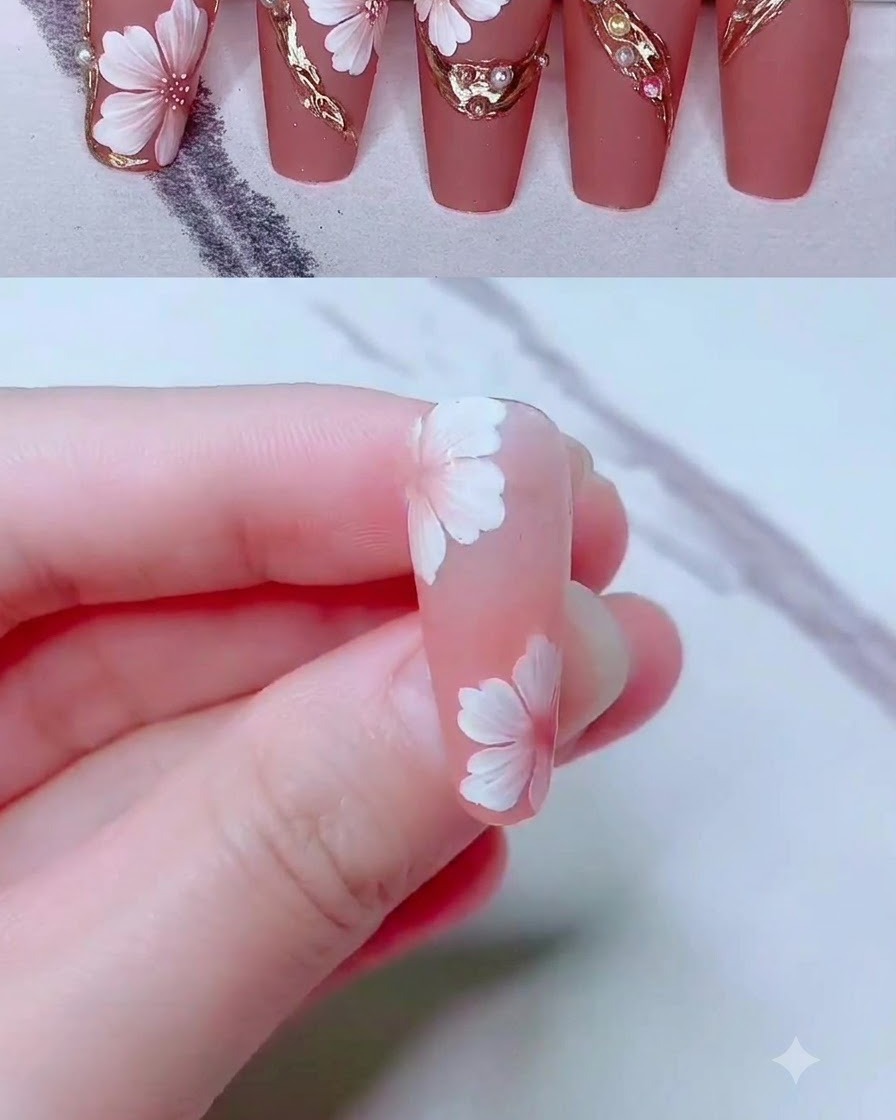 Un pincel liner fino dibujando delicadas líneas de gel dorado alrededor de un diseño de nail art floral.