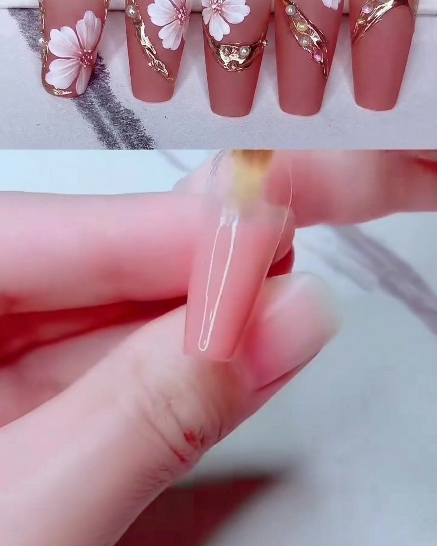 Una herramienta fina de nail art colocando pequeñas cuentas de perlas blancas sobre la superficie de la uña decorada.