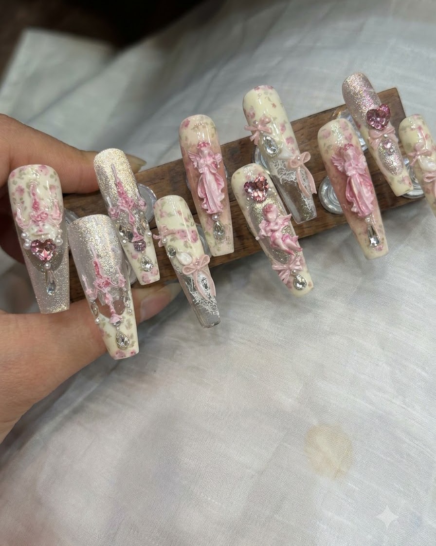 Pinzas colocando un dije de lazo 3D y pedrería sobre una uña terminada.