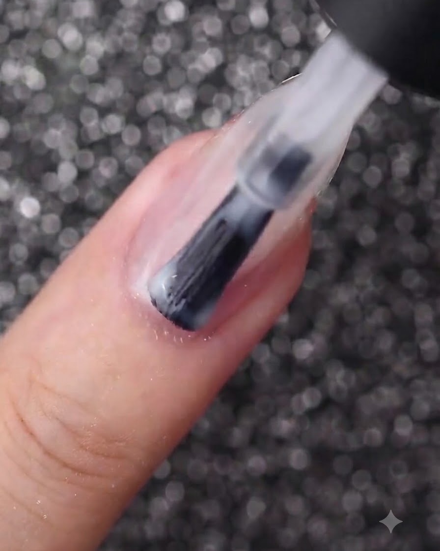 Un pincel de uñas aplicando una capa uniforme de esmalte en gel blanco lechoso sobre una uña de forma ovalada.