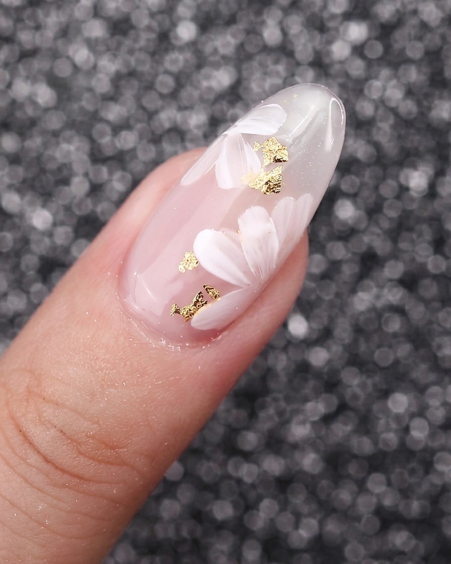 Un primer plano de pétalos de flores blancas pintados superponiéndose entre sí sobre un fondo de uña de gel.