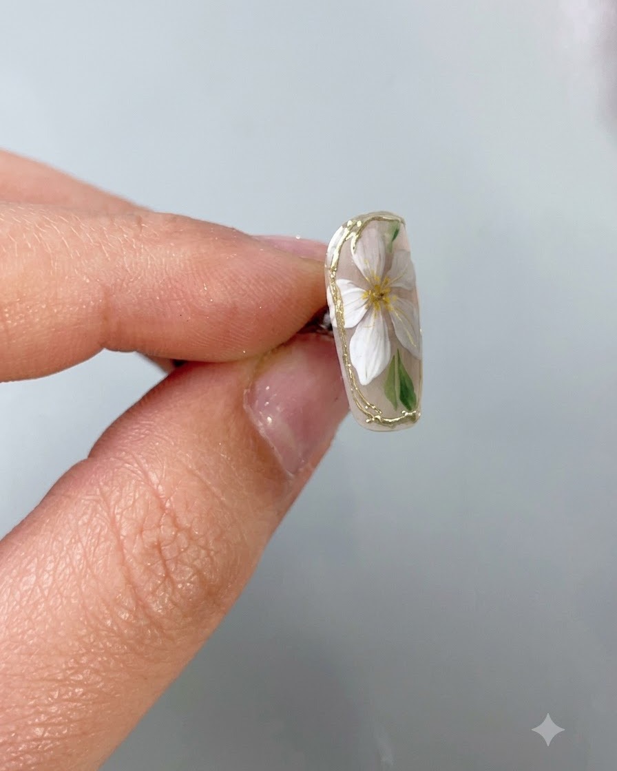Un pincel fino para uñas que aplica una capa superior protectora transparente con precisión sobre un delicado borde de cromo dorado en una uña base nude.