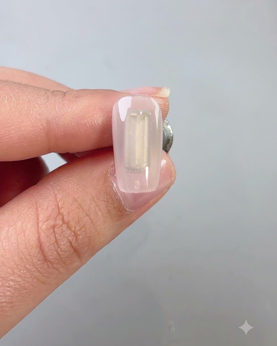 Un pincel de uñas que aplica una capa de gel ojo de gato wilderness verde oscuro uniformemente sobre una uña.