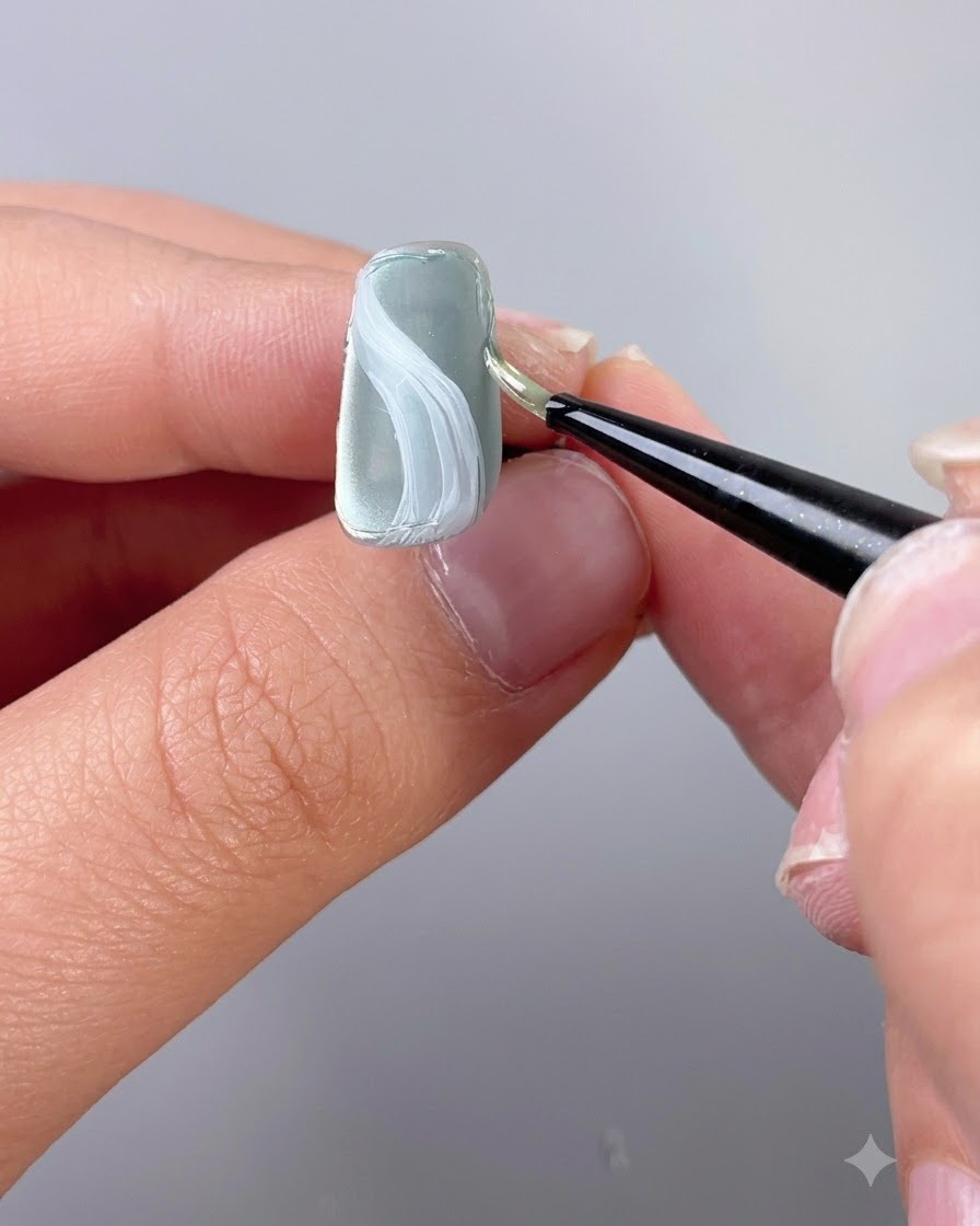 Un pincel de detalle fino que aplica gel de escultura de textura a lo largo del borde de una uña.