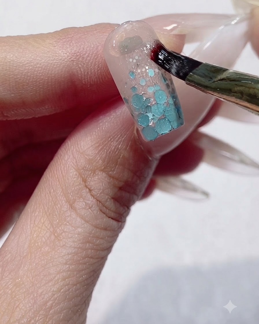 Un pincel fino aplicando gel escultórico espeso en forma de U alrededor del área de la cutícula de una uña.