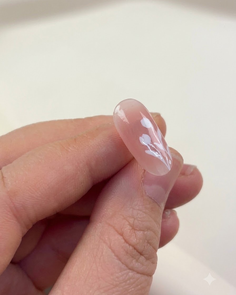 Una sola uña manicurada con arte de líneas de tulipanes blancos colocada dentro de una lámpara de curado.