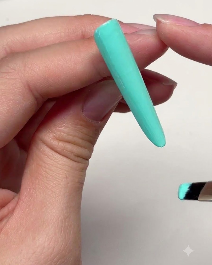 Una extensión de uña larga verde menta con una fina capa de gel aplicada cerca del límite superior de la cutícula.
