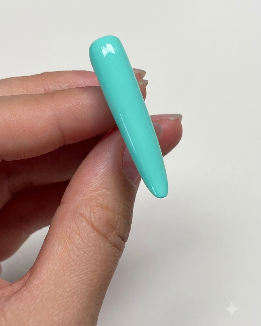 Una mano limpiando la superficie curada de la uña verde menta con una toallita con alcohol para eliminar la pegajosidad.