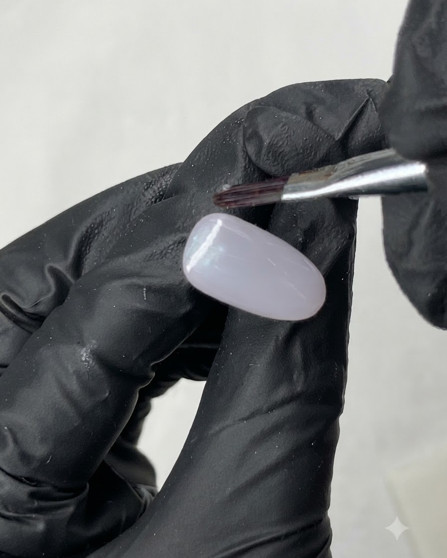 Una varita magnética sostenida sobre una uña de práctica recubierta de gel morado claro para formar una línea de ojo de gato.