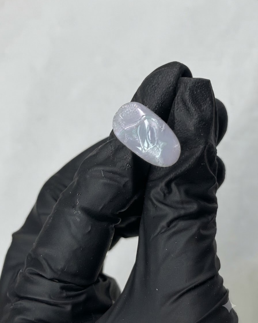 Una herramienta metálica tomando gel de construcción transparente M01 del interior de un frasco.