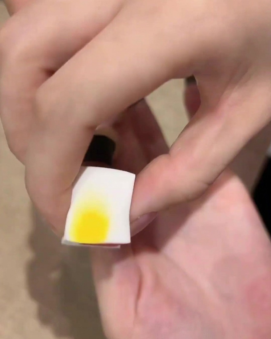 Una esponja cosmética blanca con esmalte de gel negro cerca de una uña, lista para dar toques y crear un efecto ombré.