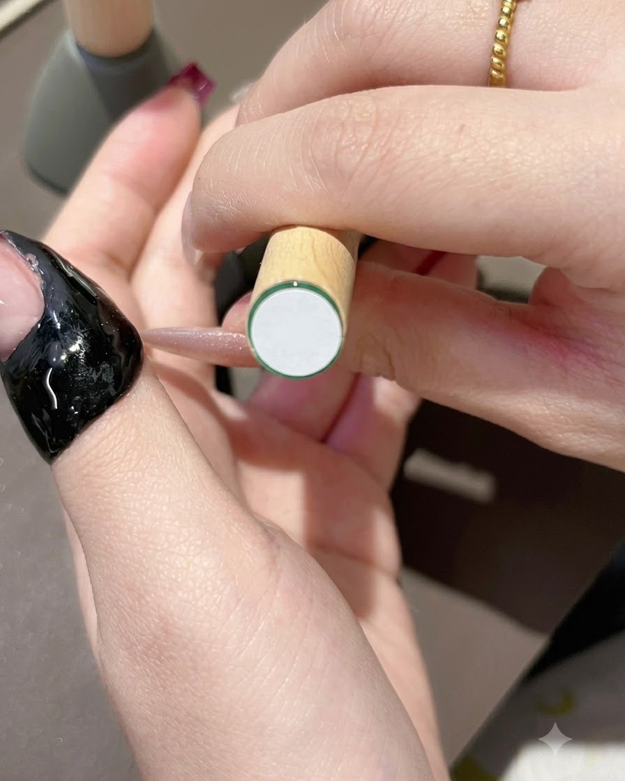 Un pincel aplicando esmalte en gel morado oscuro sobre la punta de una uña de aspecto natural.