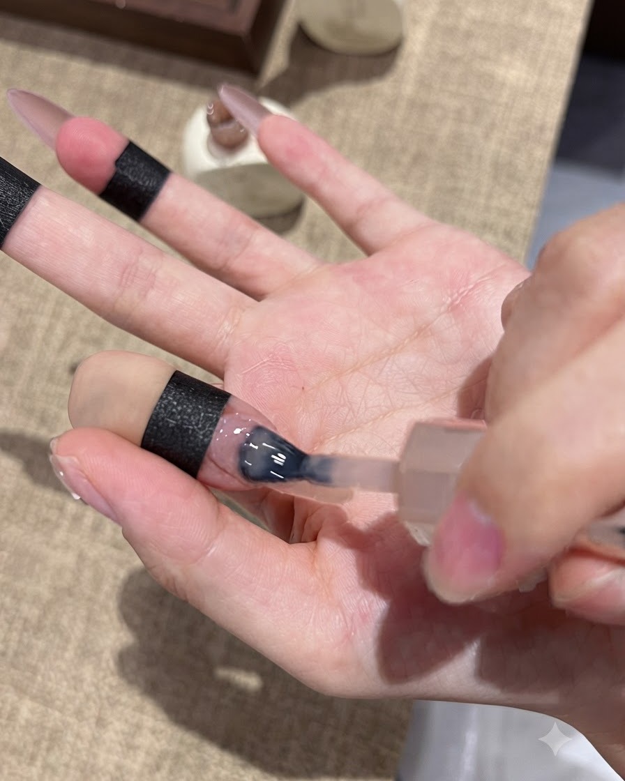 Un pincel de uñas aplicando gel ojo de gato morado en la punta de una uña para lograr un efecto ombré.