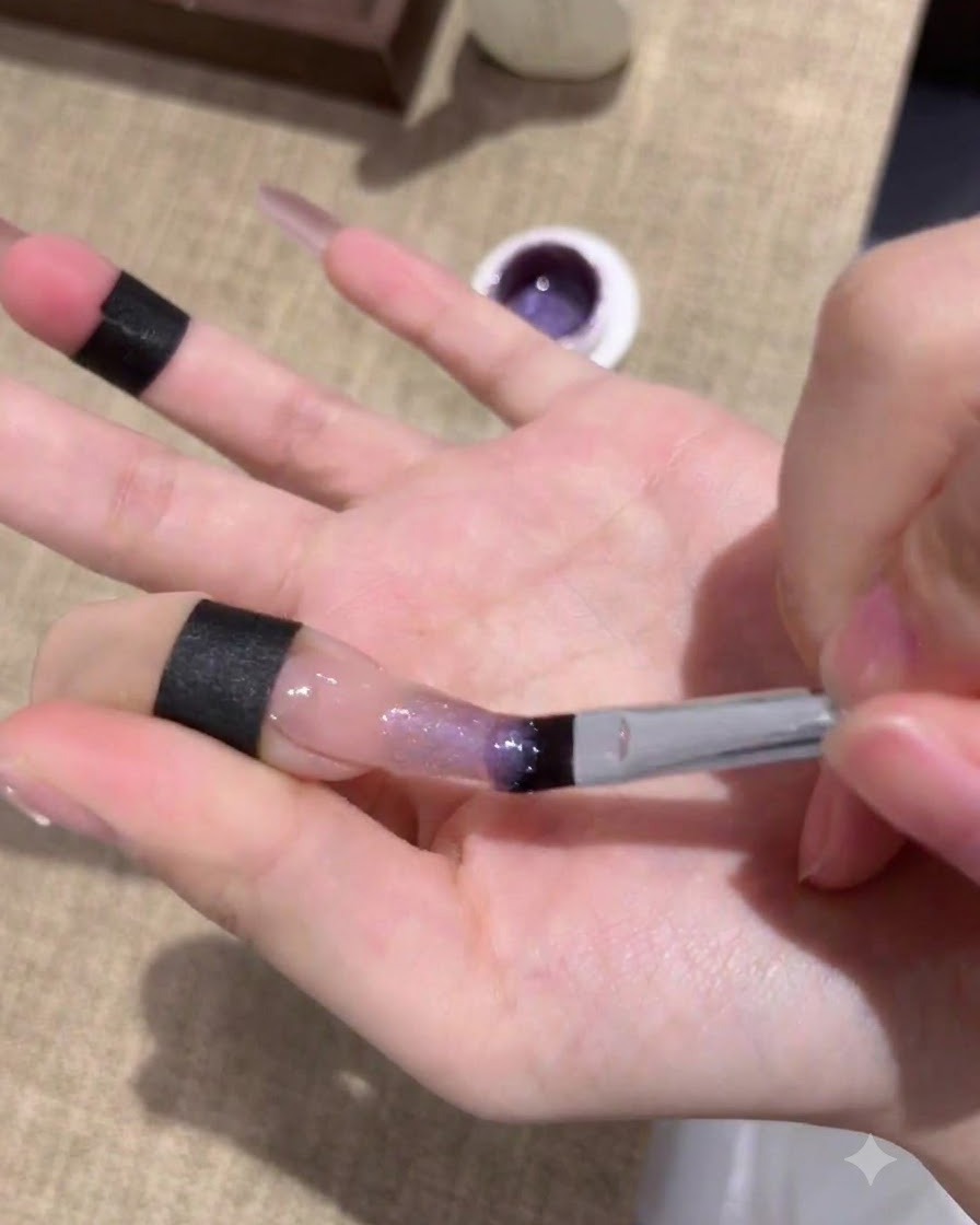 Uñas curándose bajo una lámpara UV/LED después de aplicar la primera capa de gel ojo de gato morado.