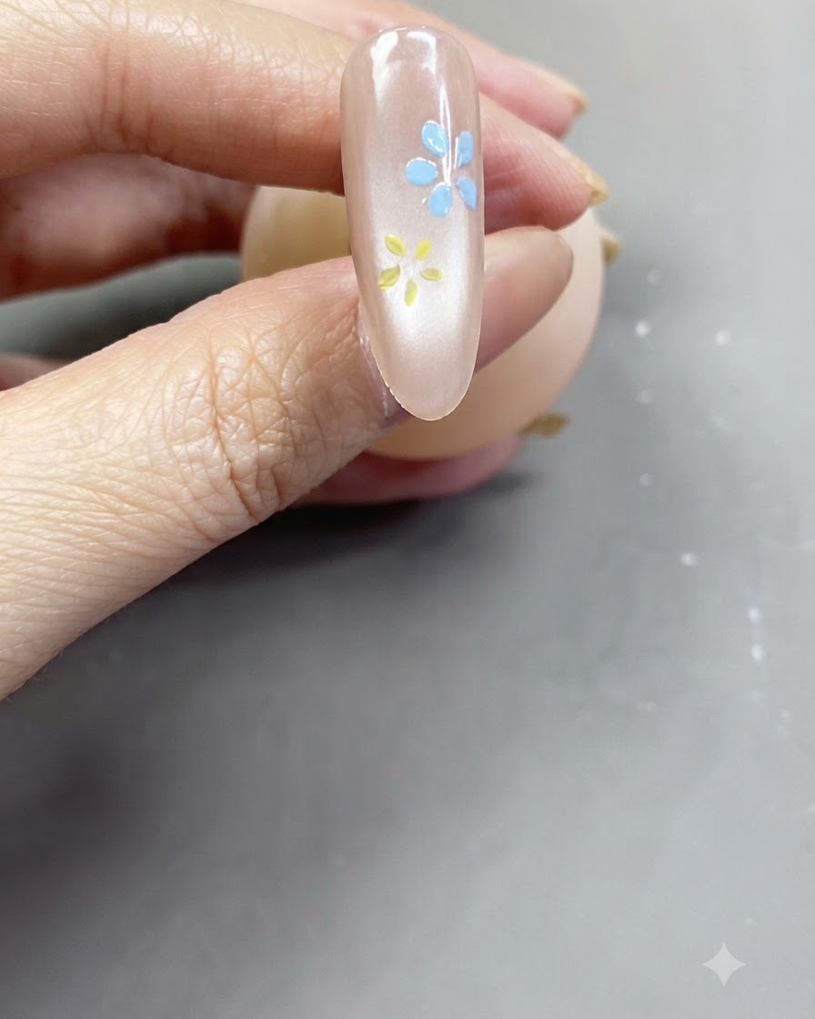 Una vista de cerca de una flor rosa suave terminada pintada sobre una uña nude rosada brillante.