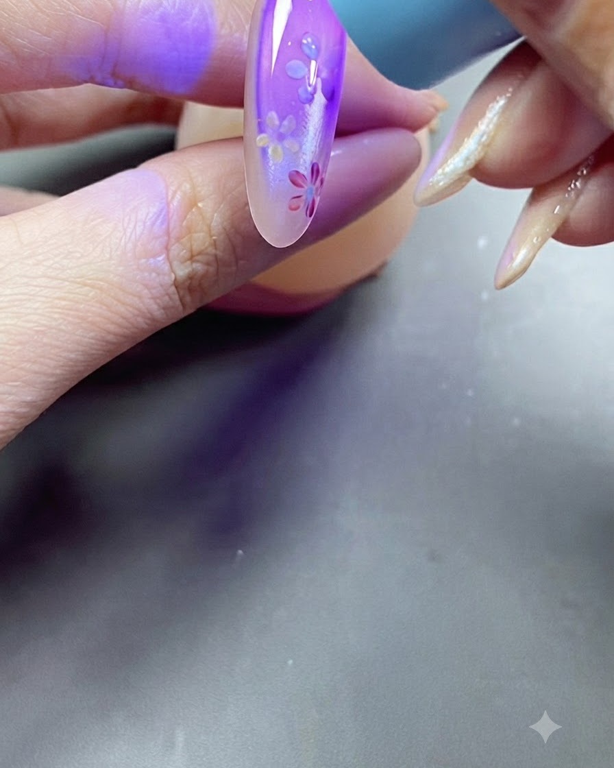 Una mano colocando una uña bajo una luz de lámpara UV morada durante el proceso de curado.