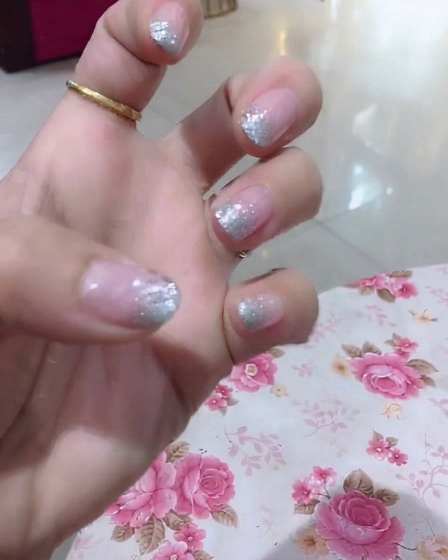 Una vista de cerca de una mano que resalta el dedo anular con brillo y finos detalles de palabras.