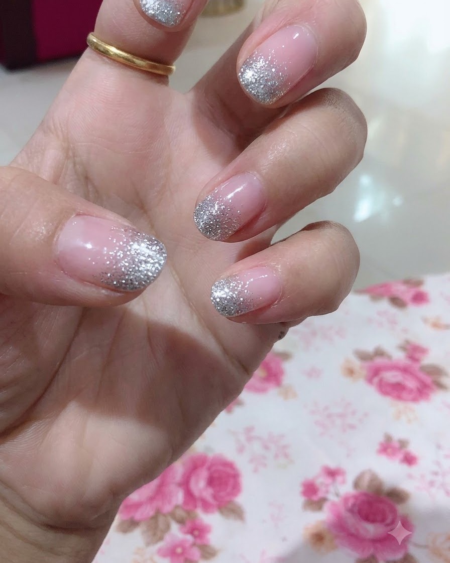Una vista de cerca de una mano que resalta el dedo medio con un diseño detallado de degradado de brillo plateado.