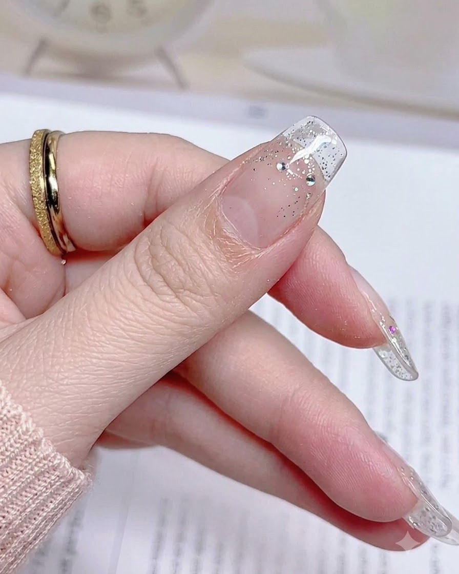 Un primer plano de una uña de pulgar terminada después de retirar el exceso de material de la pegatina, mostrando un borde limpio.