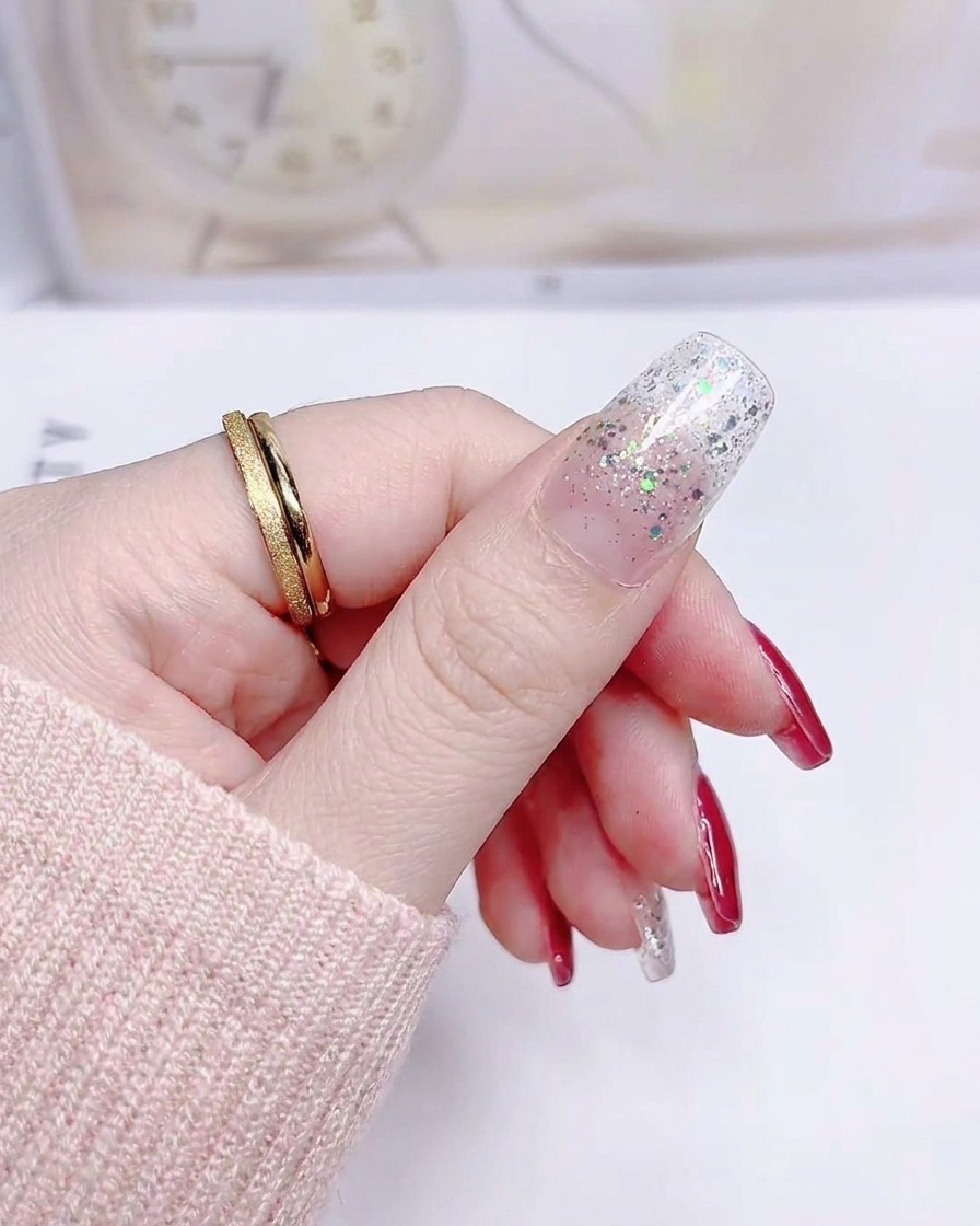 Una uña con una pegatina de degradado de glitter plateado aplicada suavemente desde la cutícula hasta la punta.