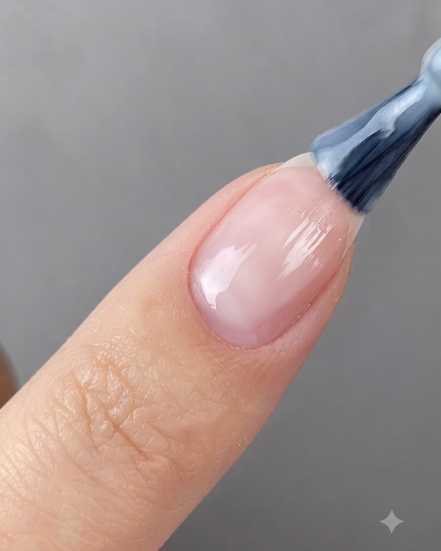 Un pincel de uñas aplicando gel blanco translúcido sobre una uña preparada.