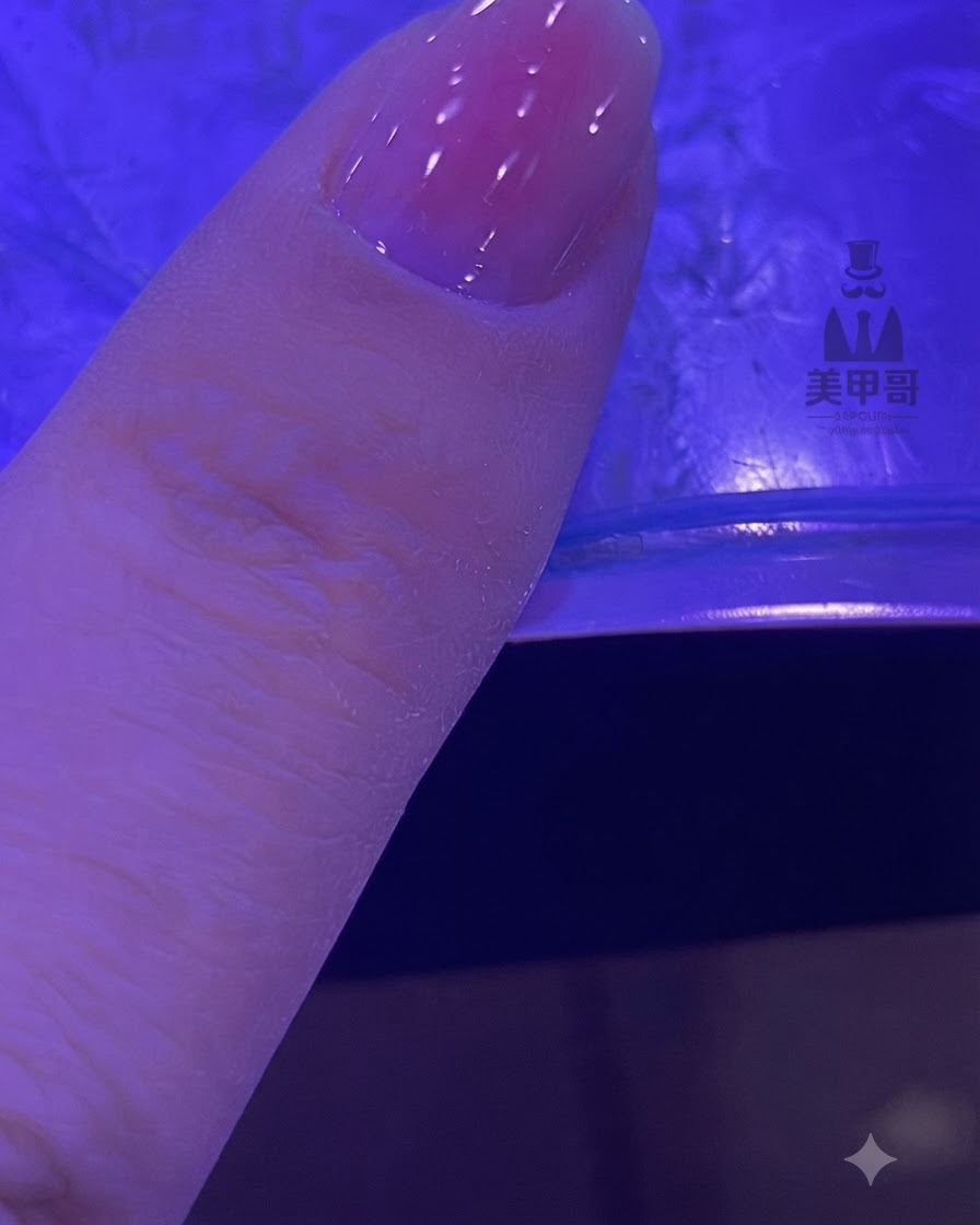 Una uña con un degradado rosa difuminado curando bajo una lámpara UV o LED.
