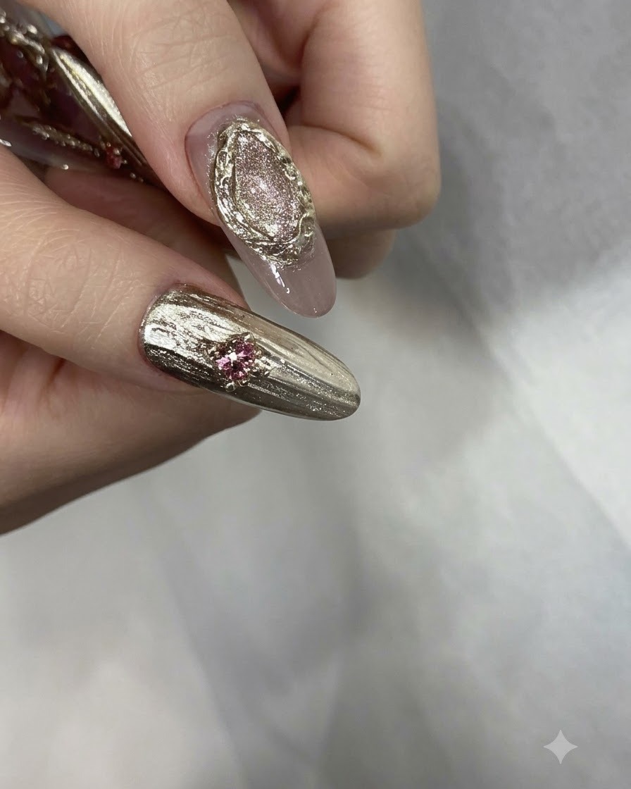 Dedos manicurados terminados adornados con pedrería rosa, cuentas doradas y detalles cromados texturizados.