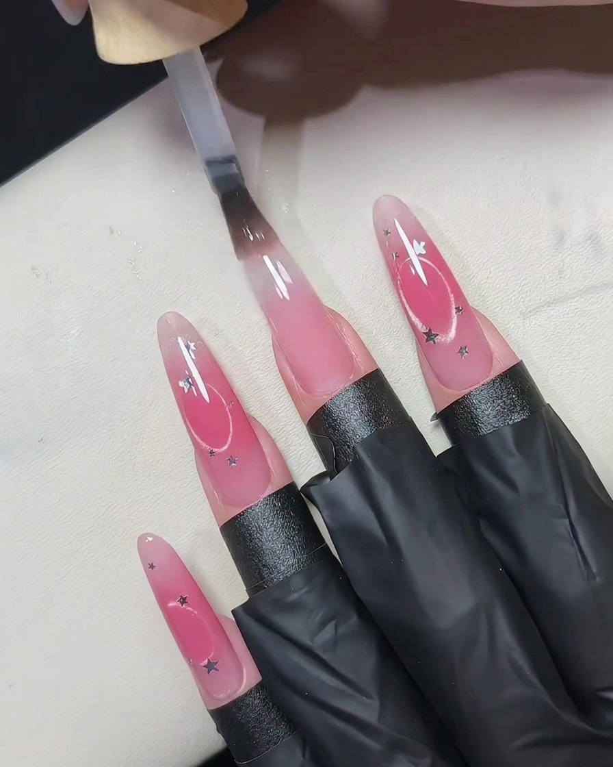 Una pequeña lámpara UV LED portátil sostenida de cerca sobre uñas postizas para curar la capa superior.