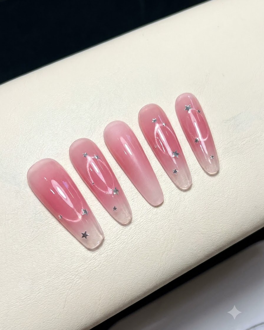 Cinco uñas postizas dispuestas sobre una superficie blanca que muestran un diseño de centro blush rosado.