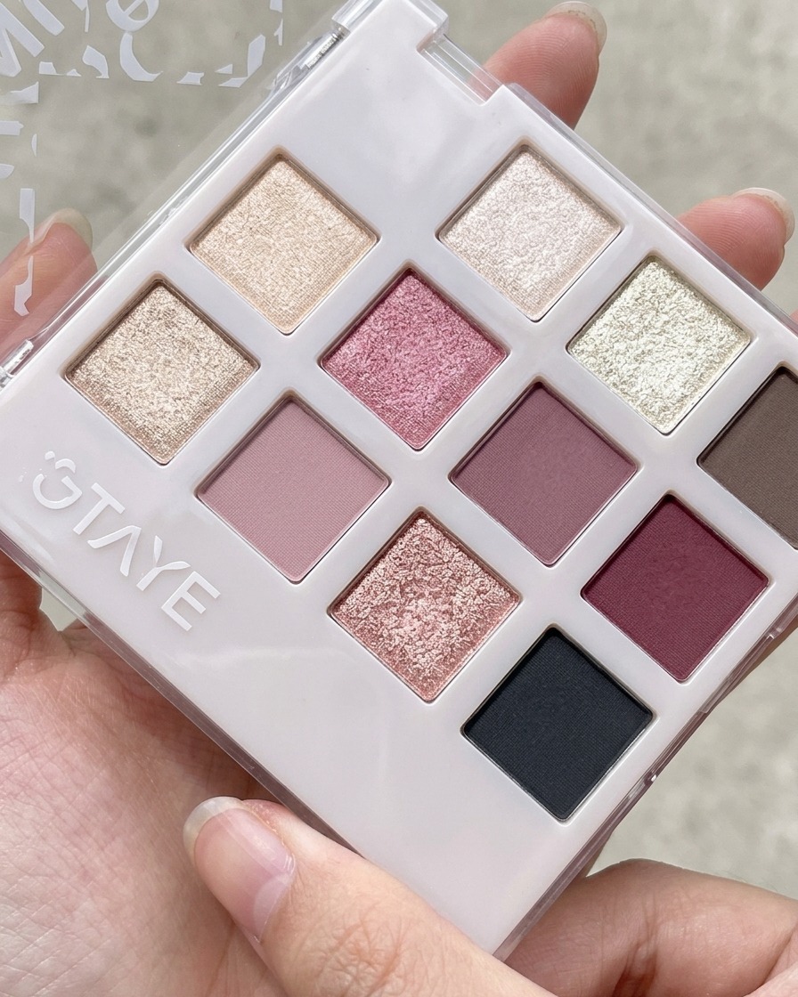 Una herramienta de silicona tomando gel rosa melocotón de una paleta con múltiples compartimentos de sombras y geles.