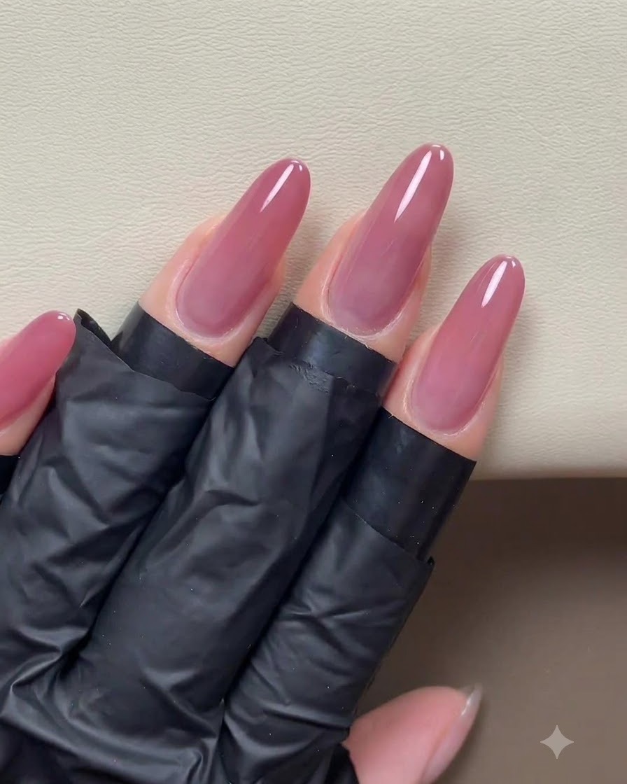 Una aplicación completa de gel ojo de gato rosa dorado cubriendo uniformemente la superficie de uñas largas preparadas.