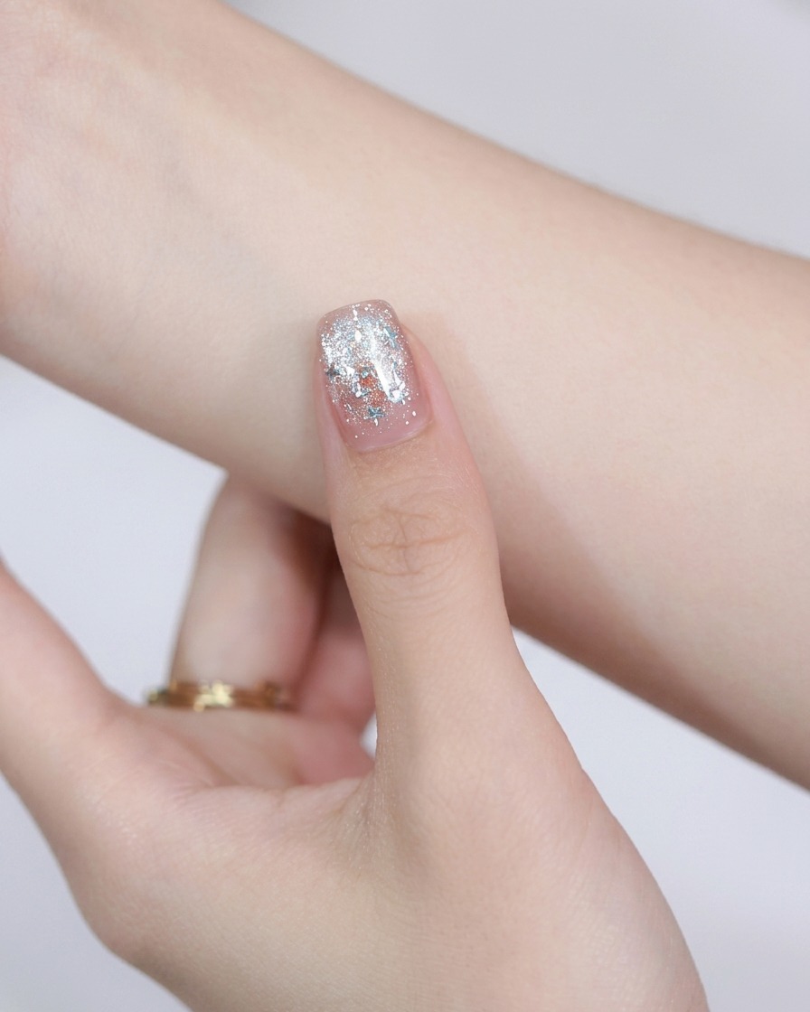 Un imán de acero redondo sostenido sobre una uña pintada para mover las partículas magnéticas del cat-eye.