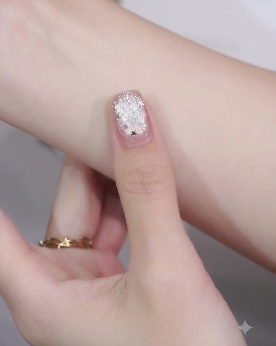Un primer plano de una uña con manicura con una pieza de brillo de estrella colocada en la punta sobre un detalle de nail art de borde.