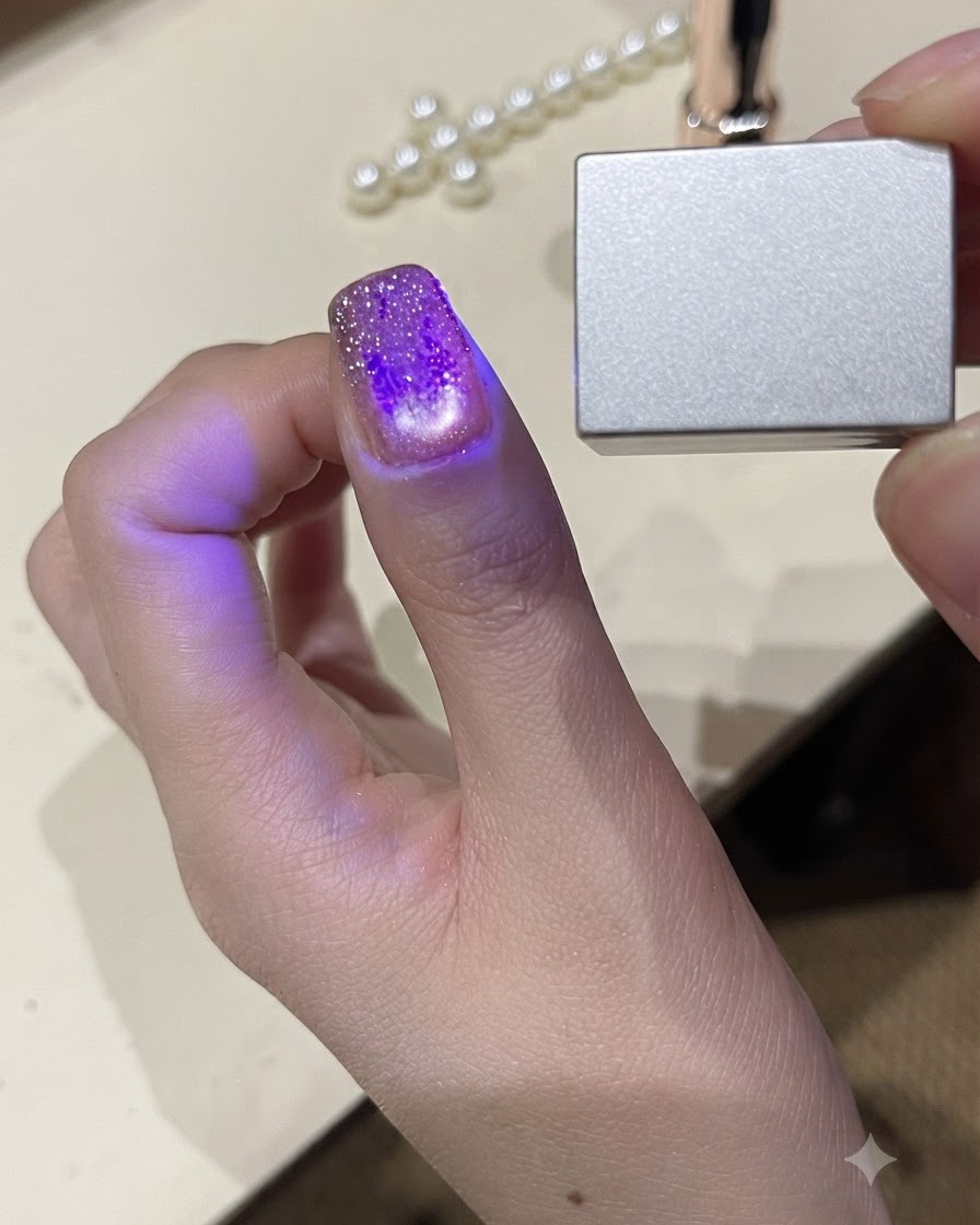 Vista de cerca de un pulgar bajo una pequeña luz UV LED portátil que cura el esmalte en gel.