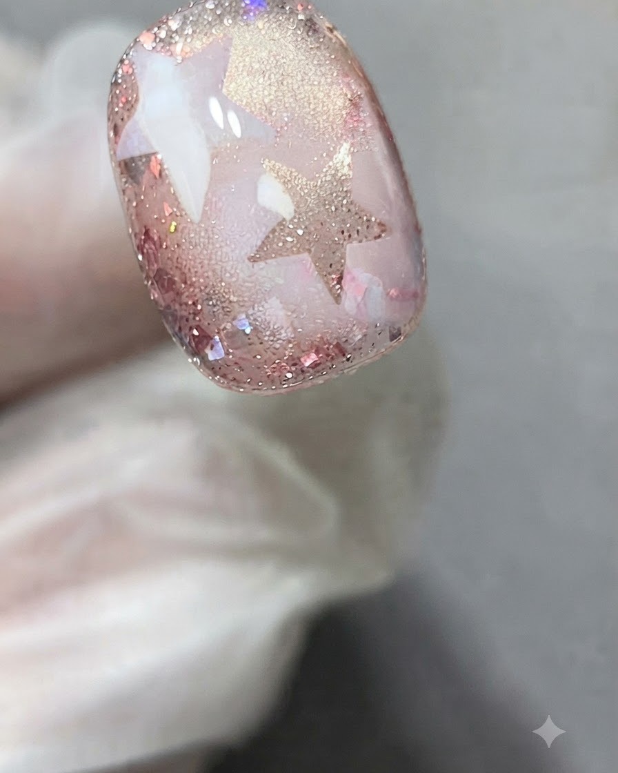 Una pegatina con plantilla de estrella aplicada precisamente sobre la superficie de una uña decorada con gel.