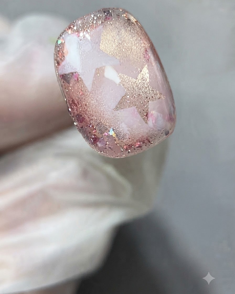 Unas pinzas o dedos con guantes despegando suavemente una plantilla de estrella del nail art curado.