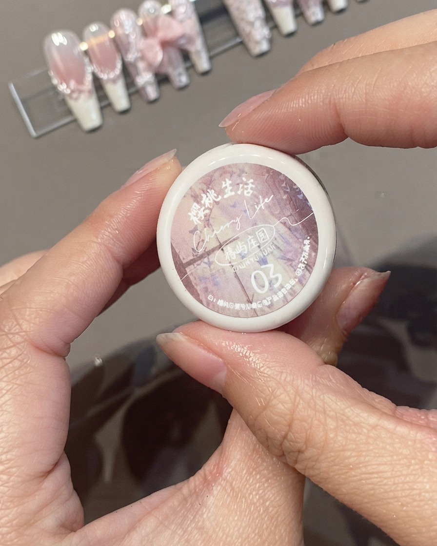 Manos sosteniendo un frasco de esmalte de gel rosa Cherry Life Spring Rain Garden 03.