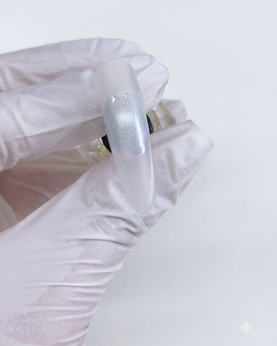 Una cuenta de gel de ojo de gato terminada en una uña después de curar bajo una lámpara.