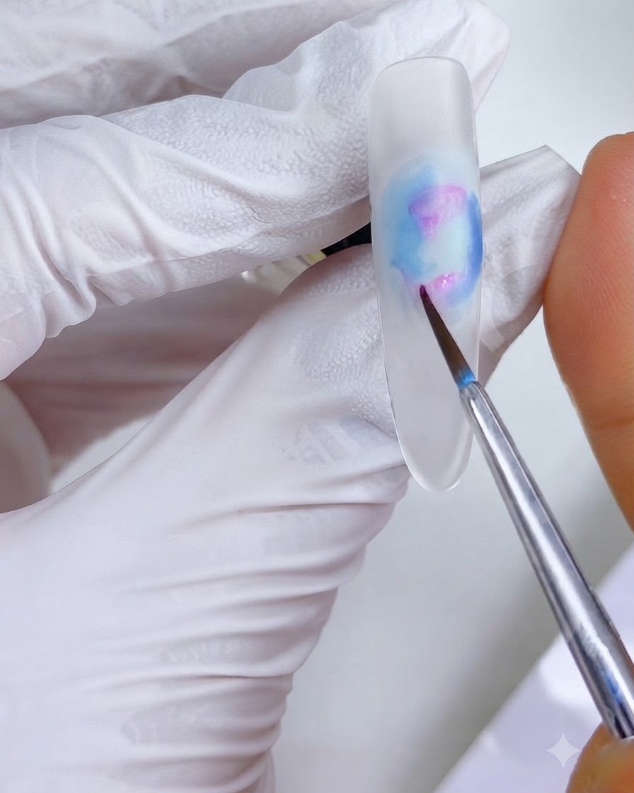 Un pincel de detalle fino aplicando pequeños puntos de tinta rosa-magenta en las regiones superior e inferior izquierda del diseño de uñas.