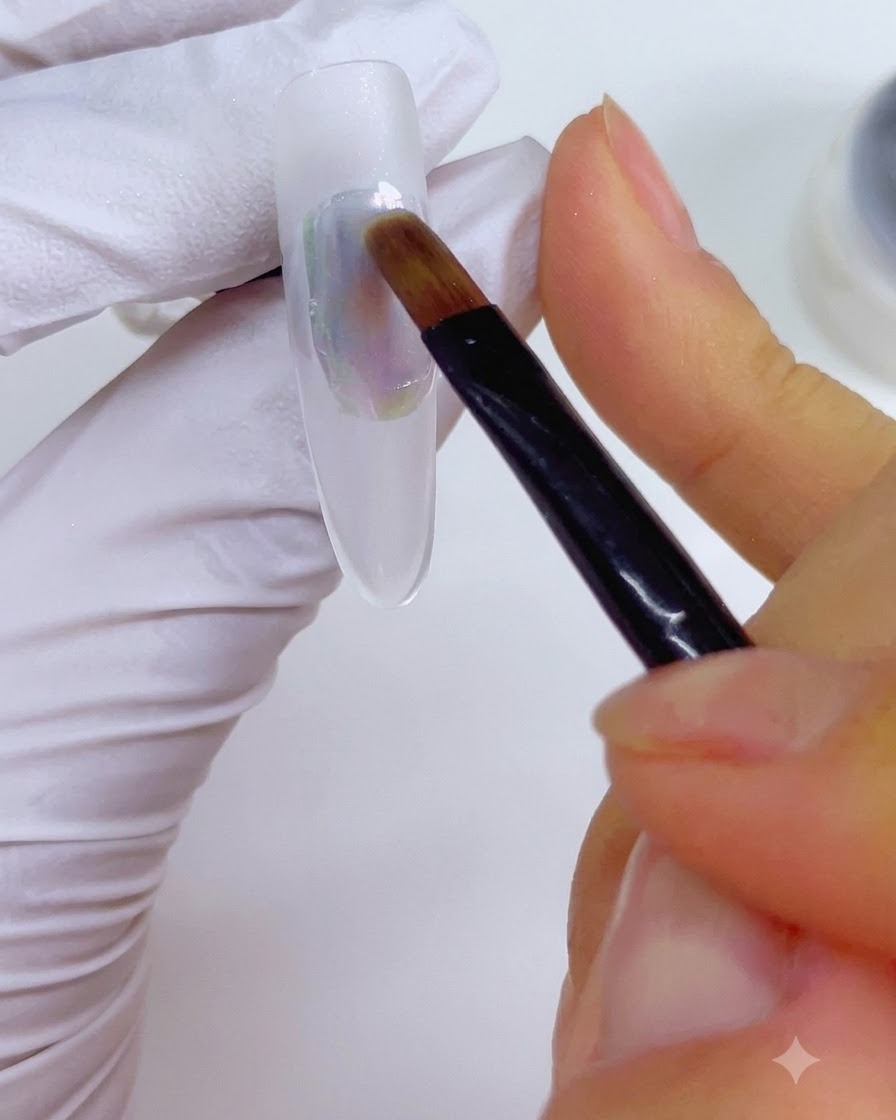 Un pincel de detalle humedecido con limpiador de uñas pasando suavemente a través de la aplicación de tinta multicolor en la uña.