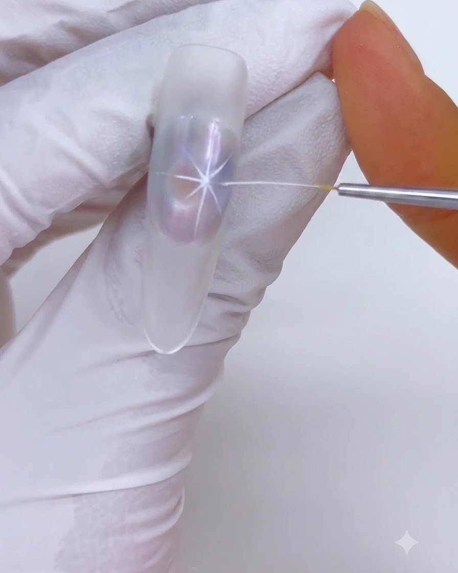 Un pincel delineador fino dibujando reflejos de ráfaga de estrellas blancas sobre un diseño de uñas translúcido.